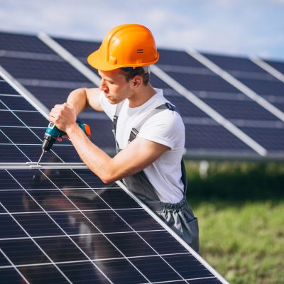 Man worker in the firld by the solar panels